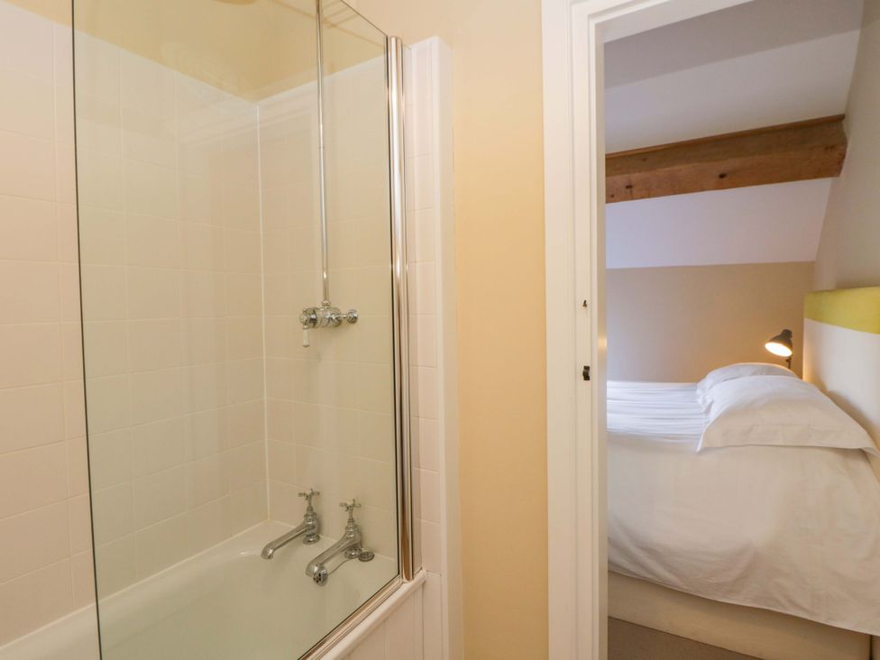A bathroom with a bathtub and shower visible next to a doorway leading to a bedroom at North Cottage in Myddfai near Llandovery
