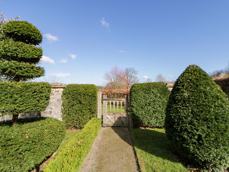 A garden with a wooden gate and trimmed hedges at North Cottage in Myddfai near Llandovery
