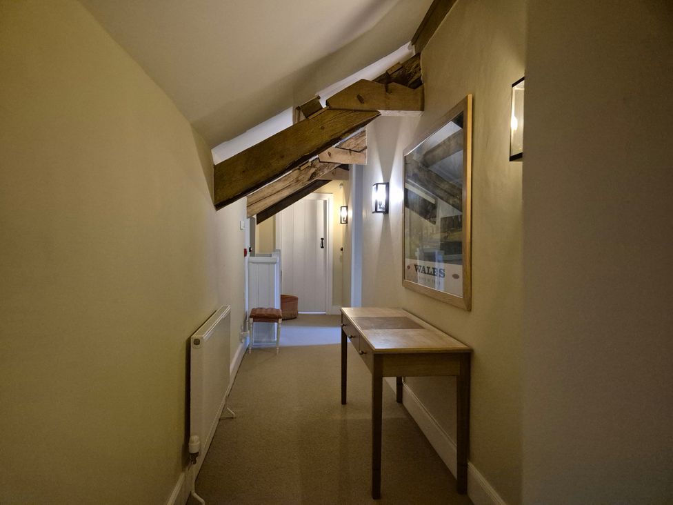 A hallway with wooden beams and a table at North Cottage in Myddfai near Llandovery