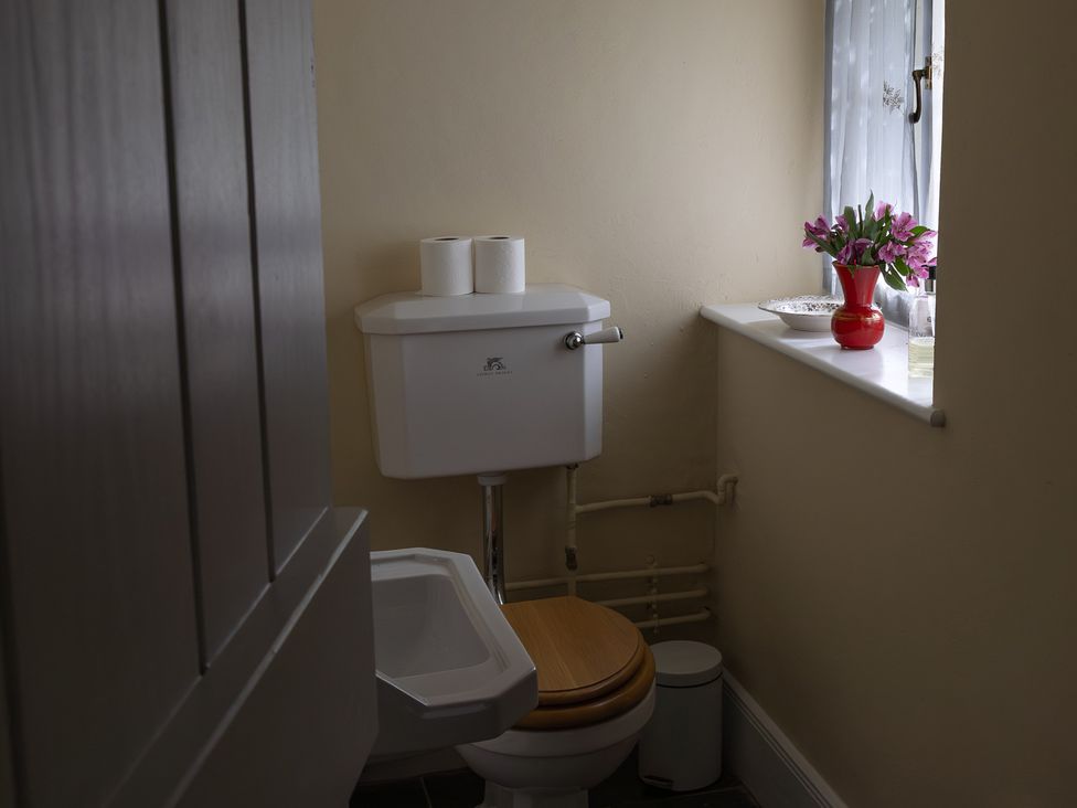 A bathroom with a toilet, tank, and a vase of flowers at North Cottage Myddfai near Llandovery