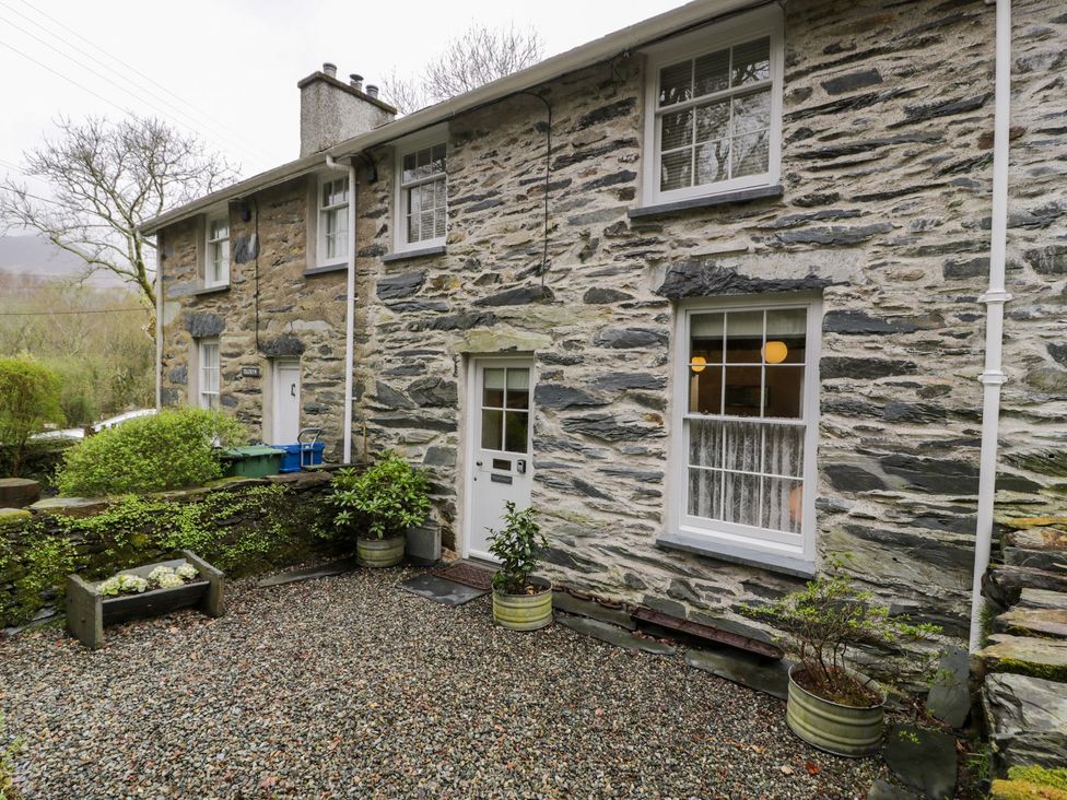 An outdoor view of a stone facade with planters and a pathway at Peniel Cottage in Caernarfon