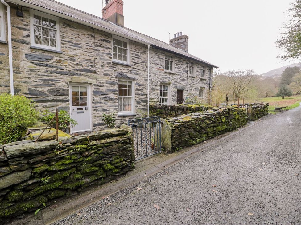A stone house with a gate and garden at Peniel Cottage in Caernarfon