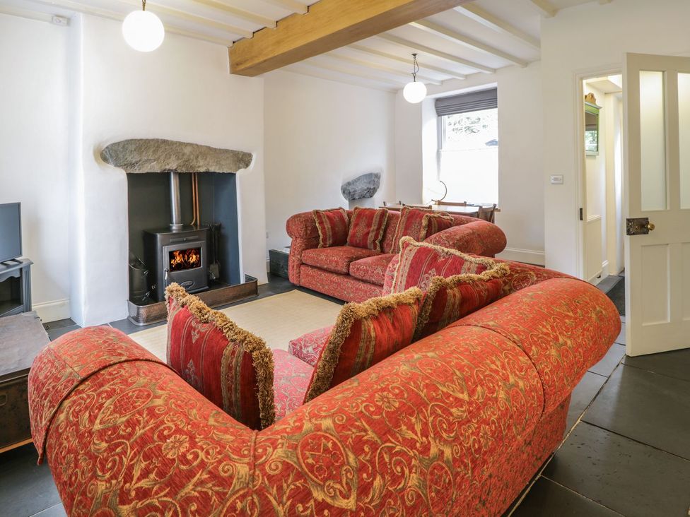 A living room with a sofa and wood stove at Peniel Cottage in Caernarfon