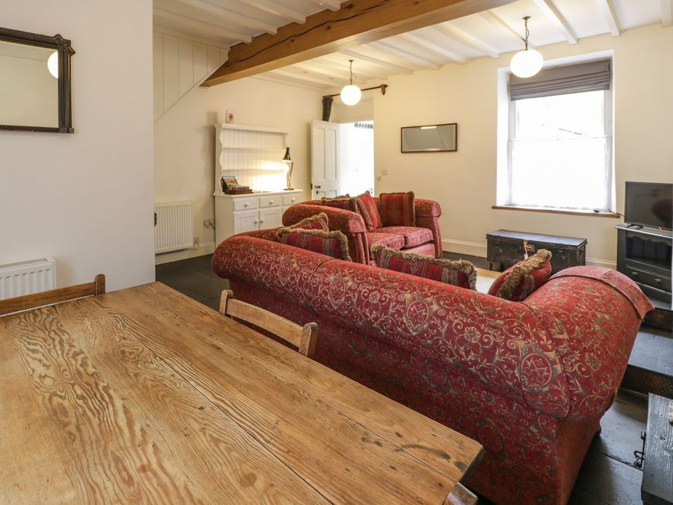 A living room with a sofa, table, and television at Peniel Cottage in Caernarfon