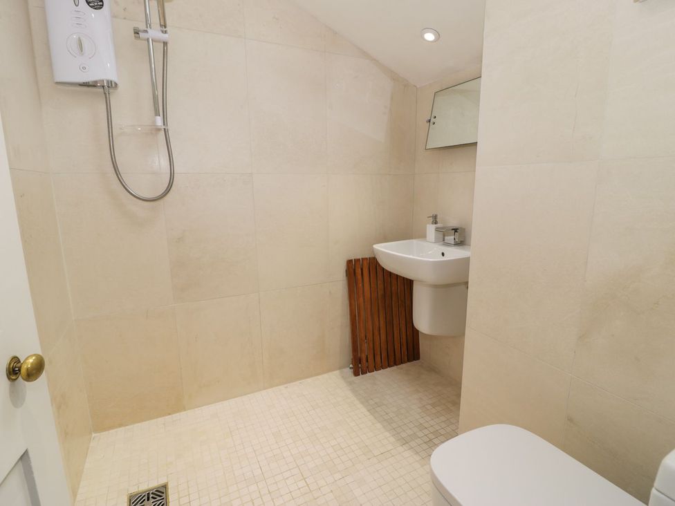 A bathroom with a shower, sink, toilet and towel rack at Peniel Cottage, Caernarfon