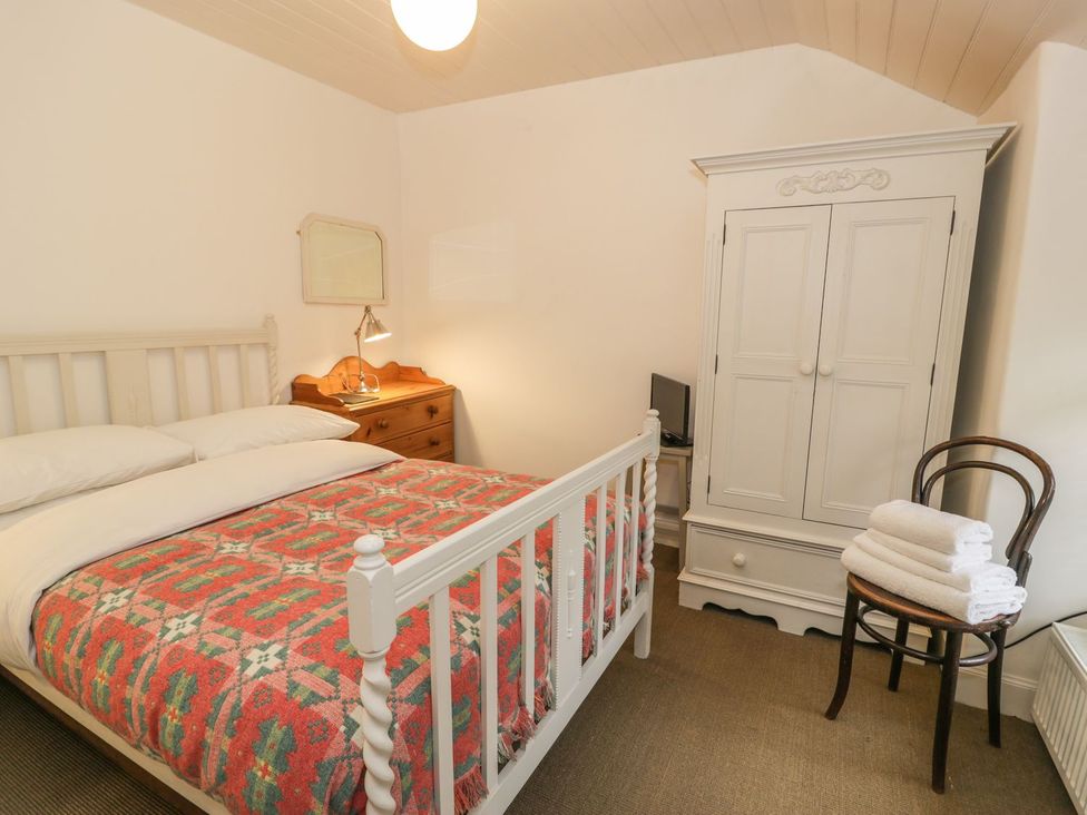 A bedroom with a bed and dresser at Peniel Cottage in Caernarfon
