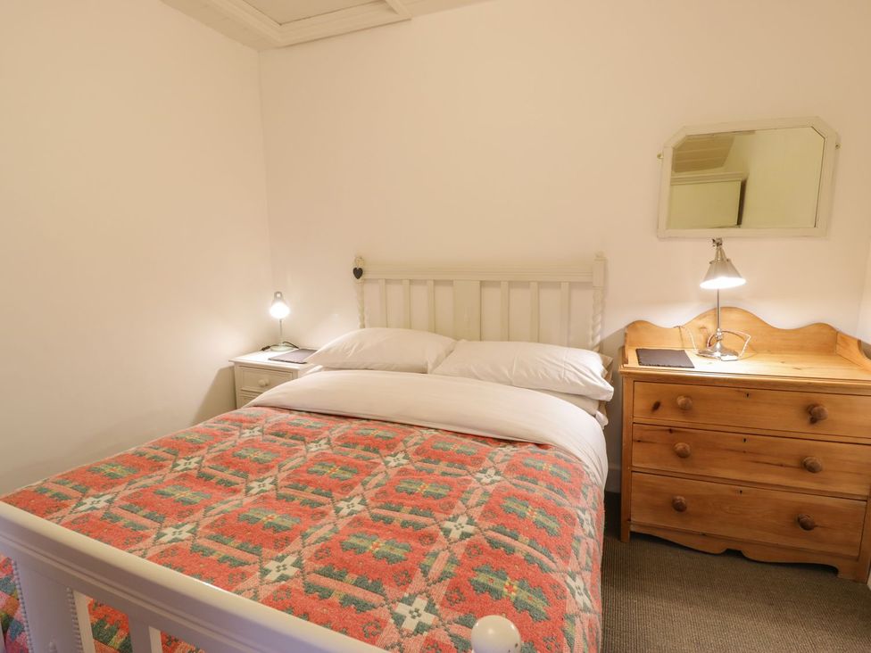 A bedroom with a bed, side table, and lamp at Peniel Cottage Caernarfon