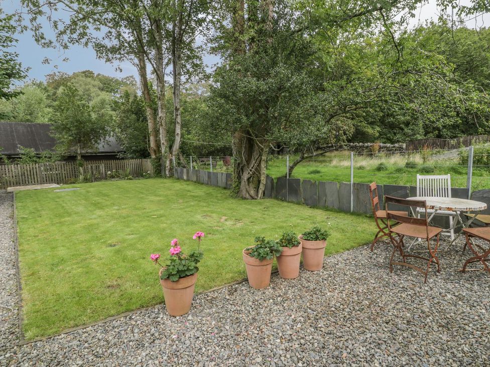 A garden with grass, a table, chairs, and planters at Peniel Cottage in Caernarfon