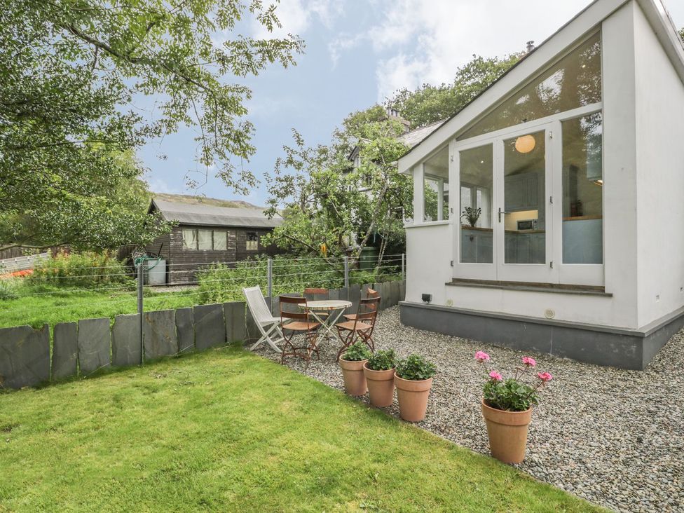 A garden with a house, table, and chairs at Peniel Cottage Caernarfon