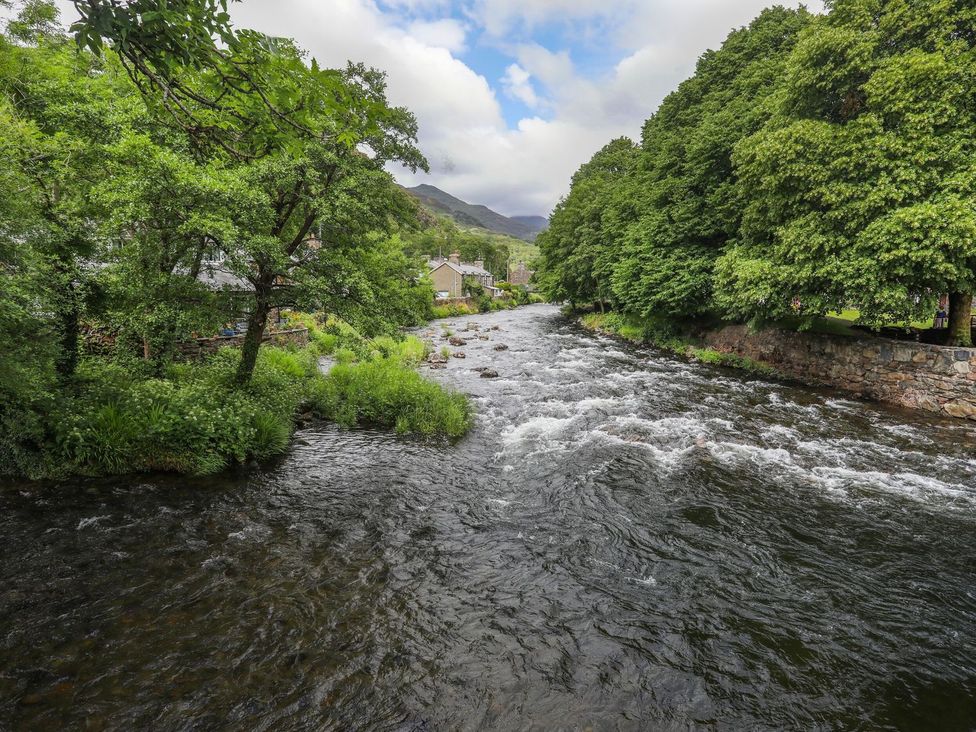 A river surrounded by trees and houses at Peniel Cottage in Caernarfon