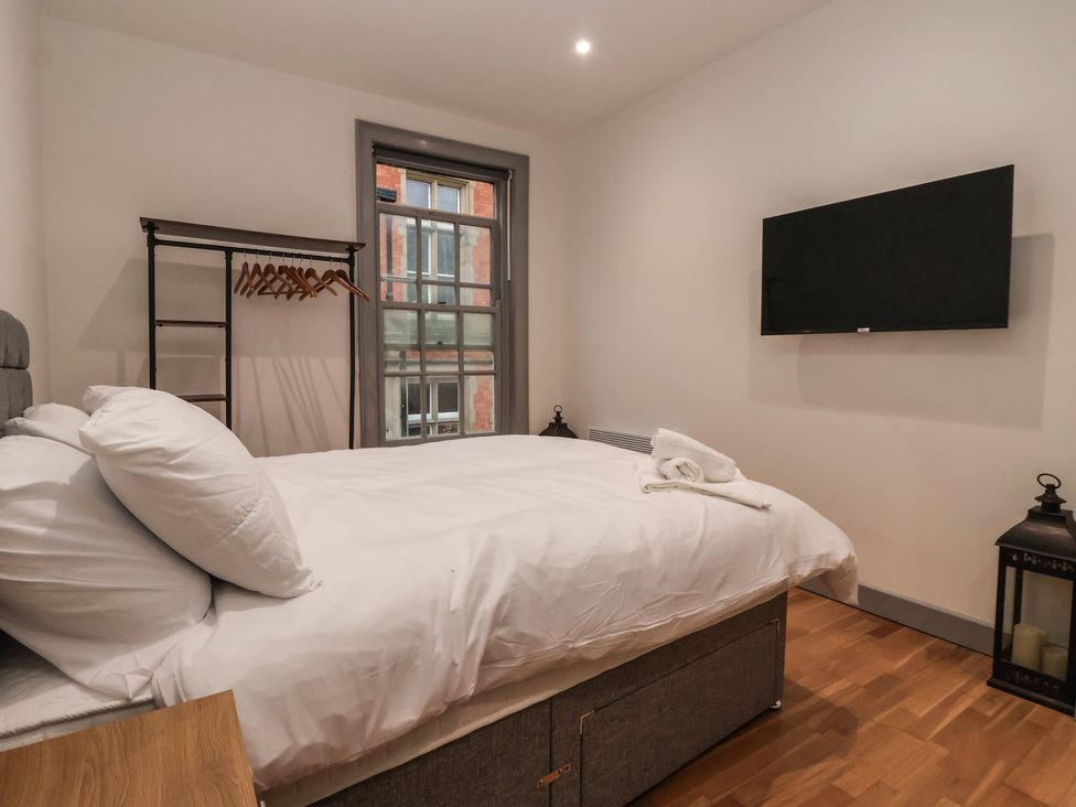 A bedroom with a bed, clothes rack, and tv at Apartment 10 in York
