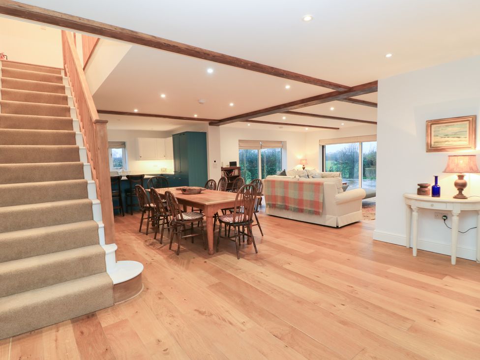 A living room with a staircase, dining table, and sofa at Peewit Coach House in Moreton-in-Marsh