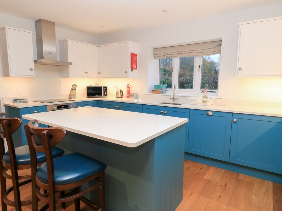 A kitchen with an island and microwave at Peewit Coach House in Moreton-in-Marsh