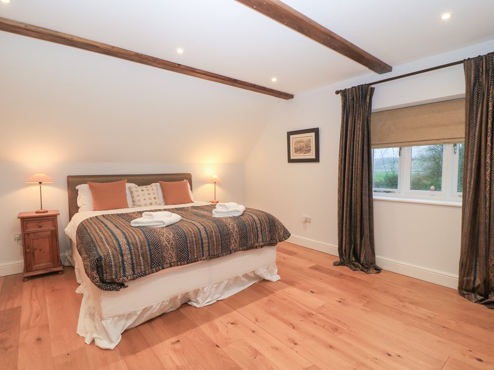A bedroom with a bed and nightstand at Peewit Coach House in Moreton-in-Marsh