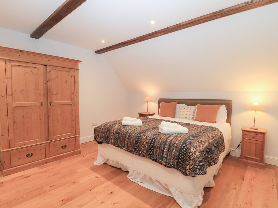 A bedroom with a bed and wardrobe at Peewit Coach House in Moreton-in-Marsh