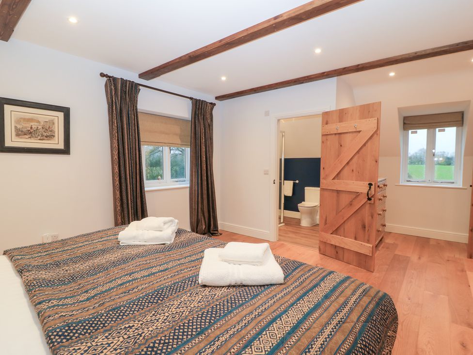 A bedroom with two beds and an en-suite bathroom at Peewit Coach House Moreton-in-Marsh