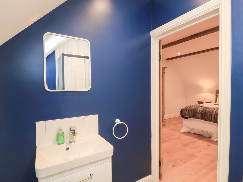 A bathroom with a sink and mirror at Peewit Coach House Moreton-in-Marsh