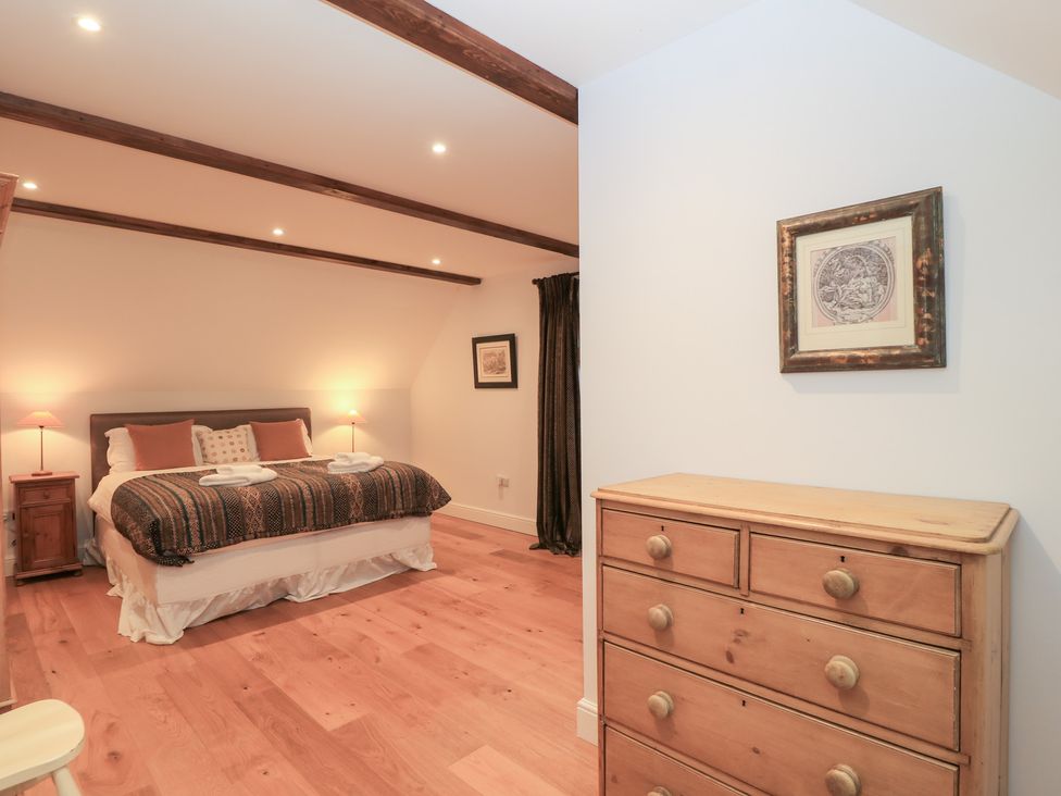 A bedroom with a bed and dresser at Peewit Coach House in Moreton-in-Marsh