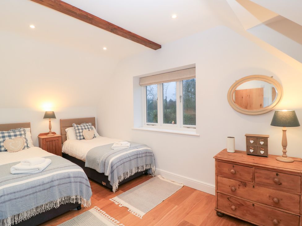 A bedroom with two beds and a window at Peewit Coach House, Moreton-in-Marsh