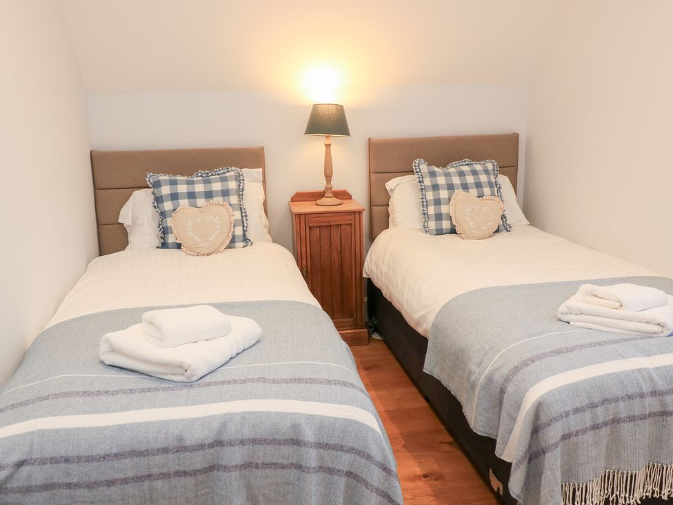 A bedroom with two single beds and a lamp at Peewit Coach House in Moreton-in-Marsh