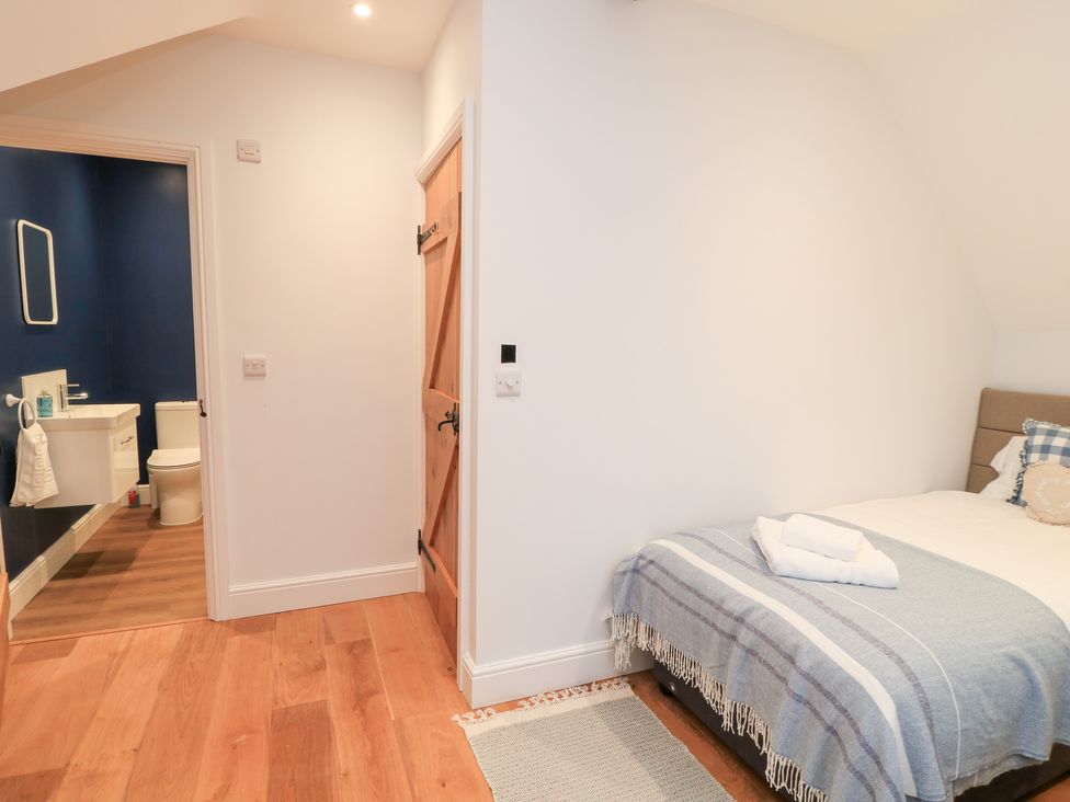 A bedroom with a bed and bathroom door at Peewit Coach House in Moreton-in-Marsh