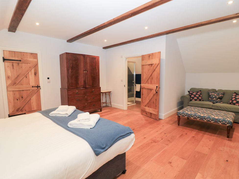 A bedroom with a bed and wardrobe at Peewit Coach House in Moreton-in-Marsh