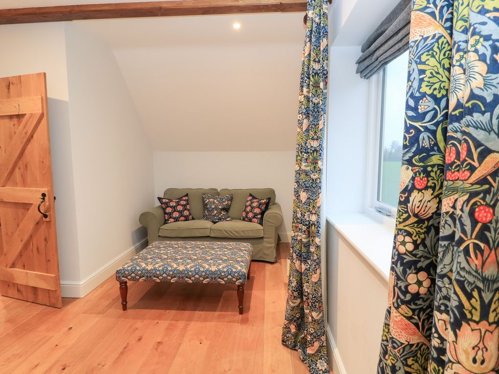 A living room with a sofa and ottoman at Peewit Coach House in Moreton-in-Marsh