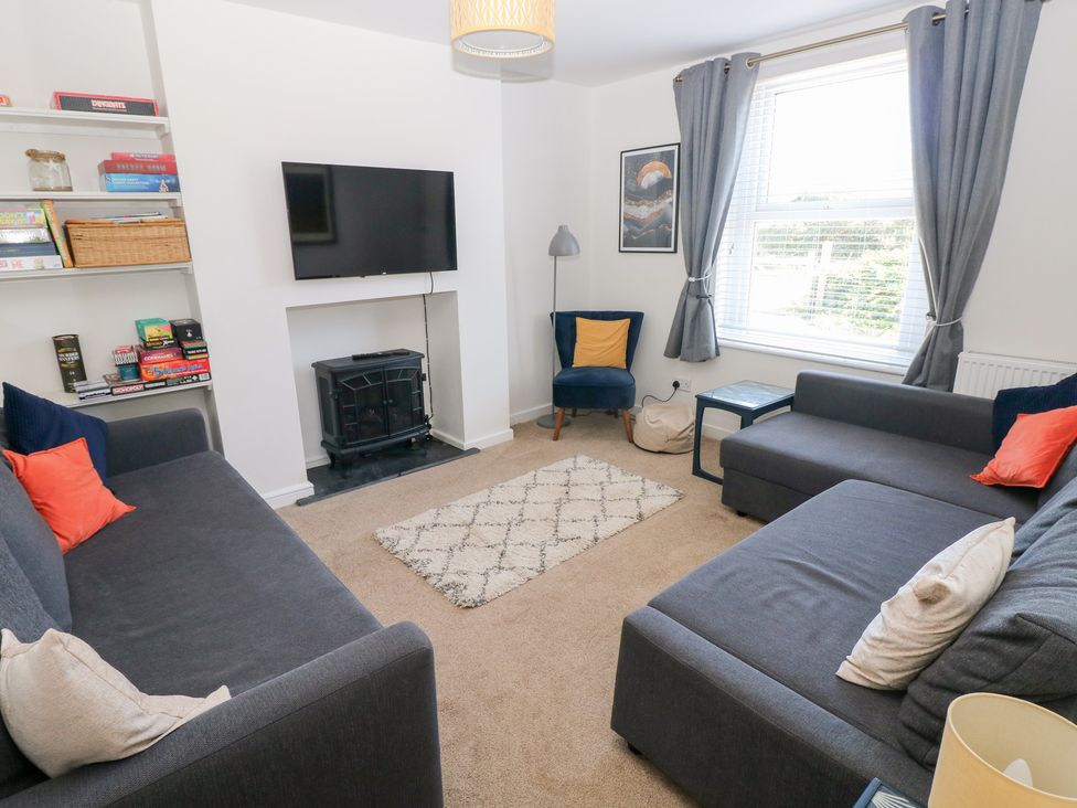 A living room with a television and a bookshelf at Hawthorns in Swansea