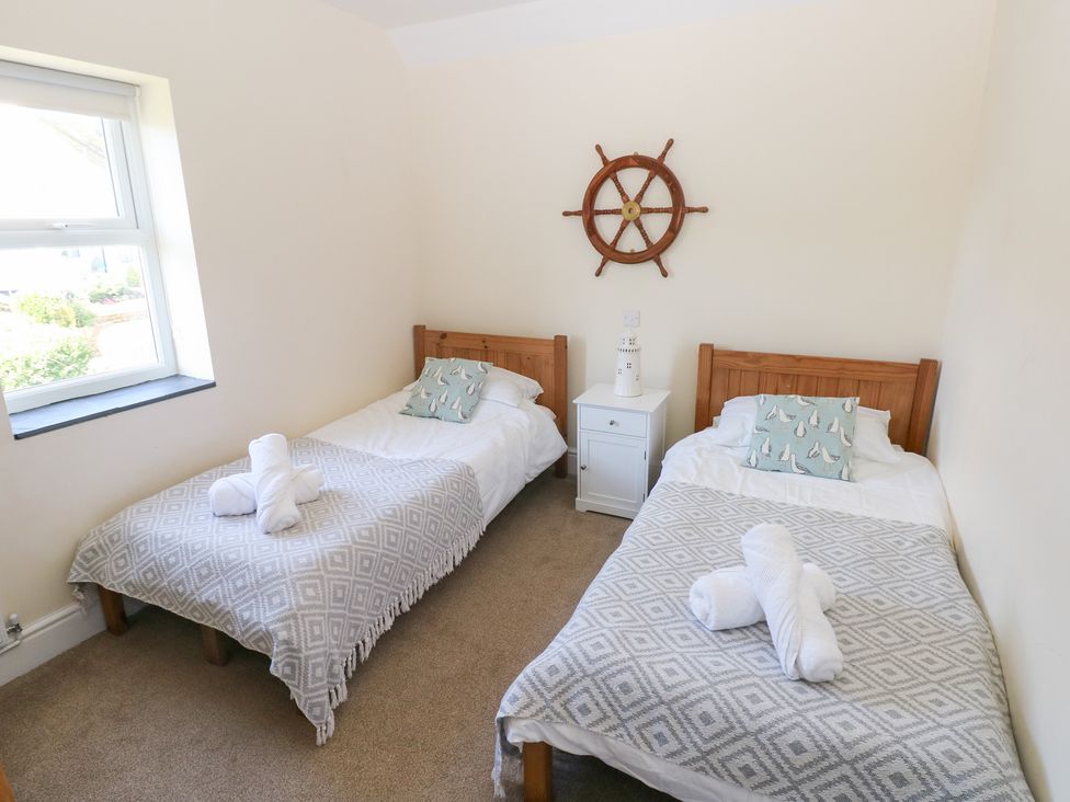 A bedroom with two beds and a bedside table at Hawthorns in Swansea
