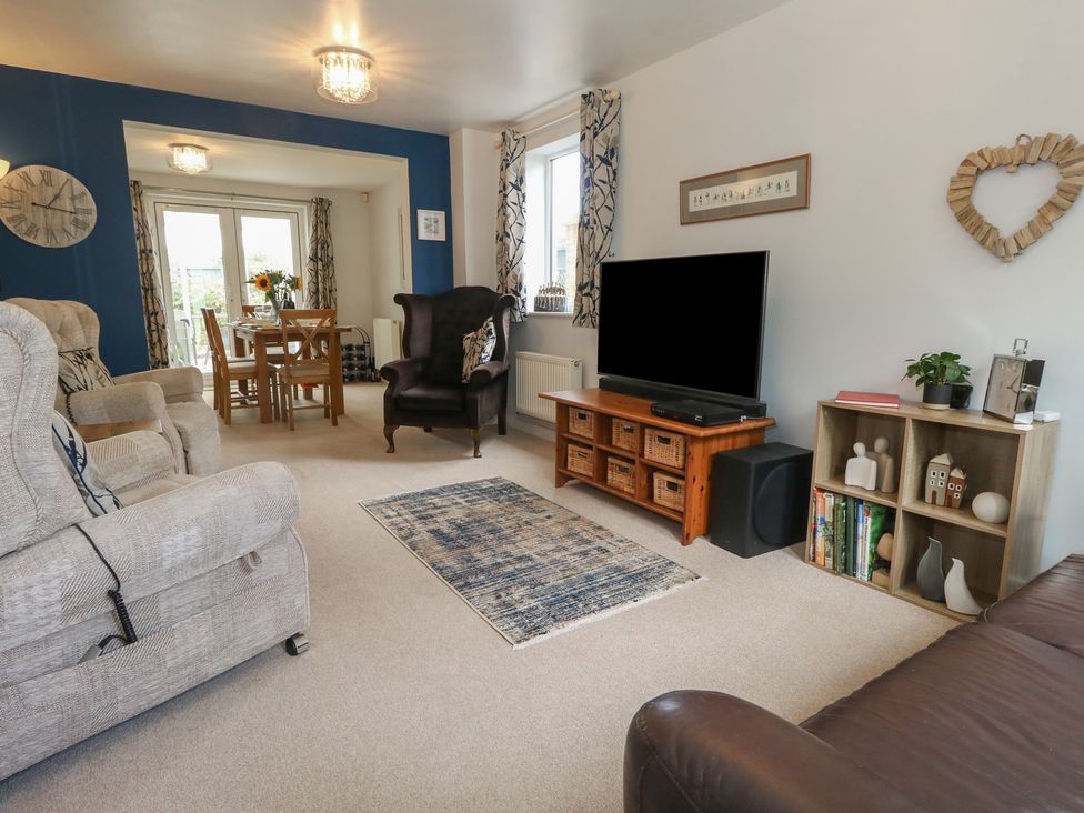 A living room with a sofa and dining area at June Cottage in Wool