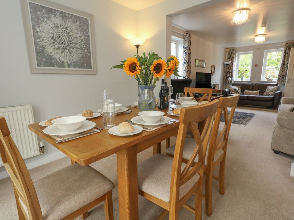 A dining room with a wooden table and chairs at June Cottage in Wool