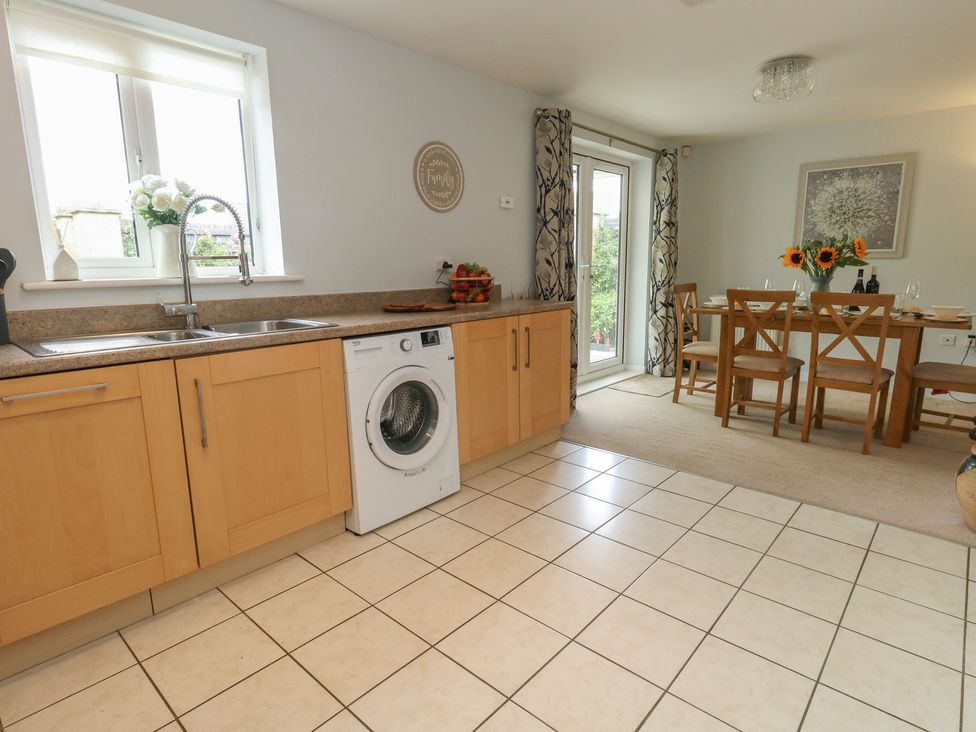 A kitchen with a wash machine and dining table at June Cottage in Wool
