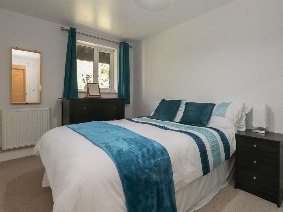A bedroom with a bed and a mirror at June Cottage in Wool