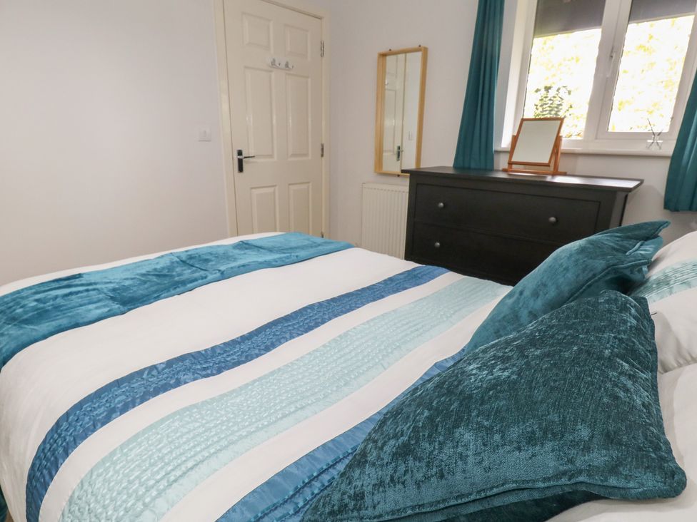 A bedroom with a bed and dresser at June Cottage in Wool