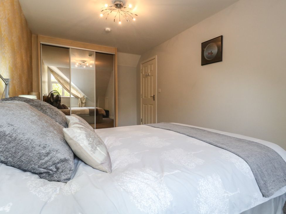A bedroom with a bed and mirrored wardrobe at June Cottage in Wool