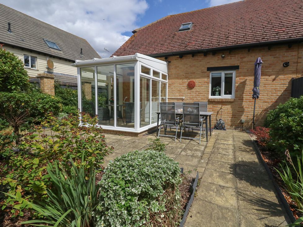 A garden with a conservatory and outdoor seating at June Cottage in Wool