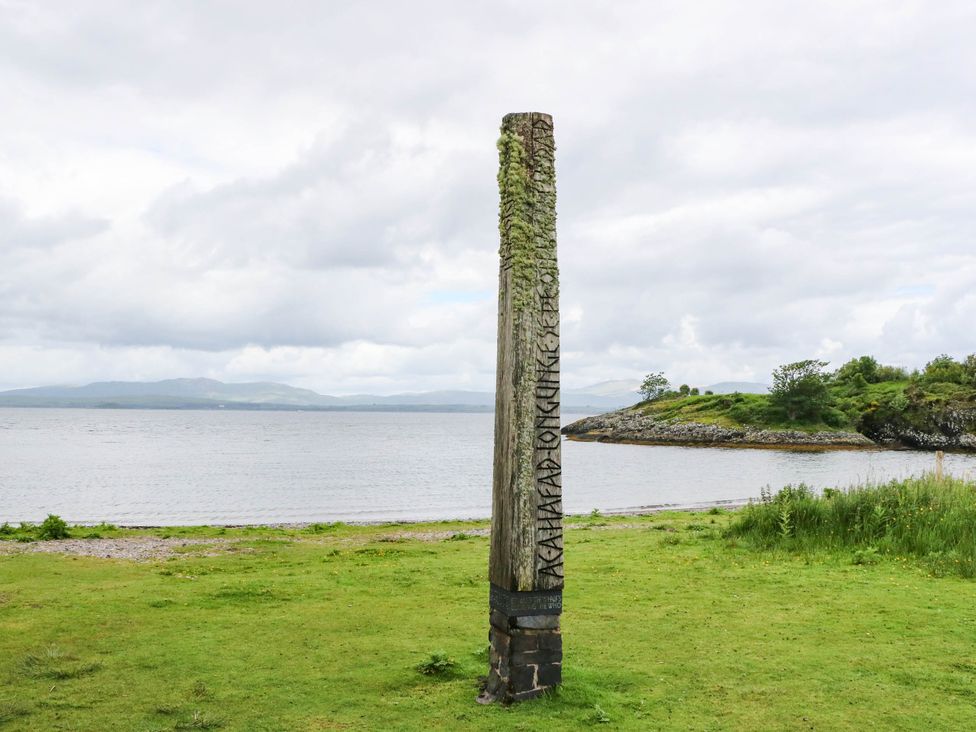 A wooden post with engraving near water at 1 Balnakeil Dunbeg