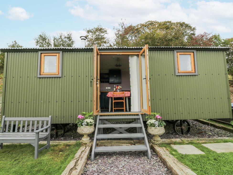 A shepherd's hut with steps and a bench at Brondel Luxury Shepherd's Hut