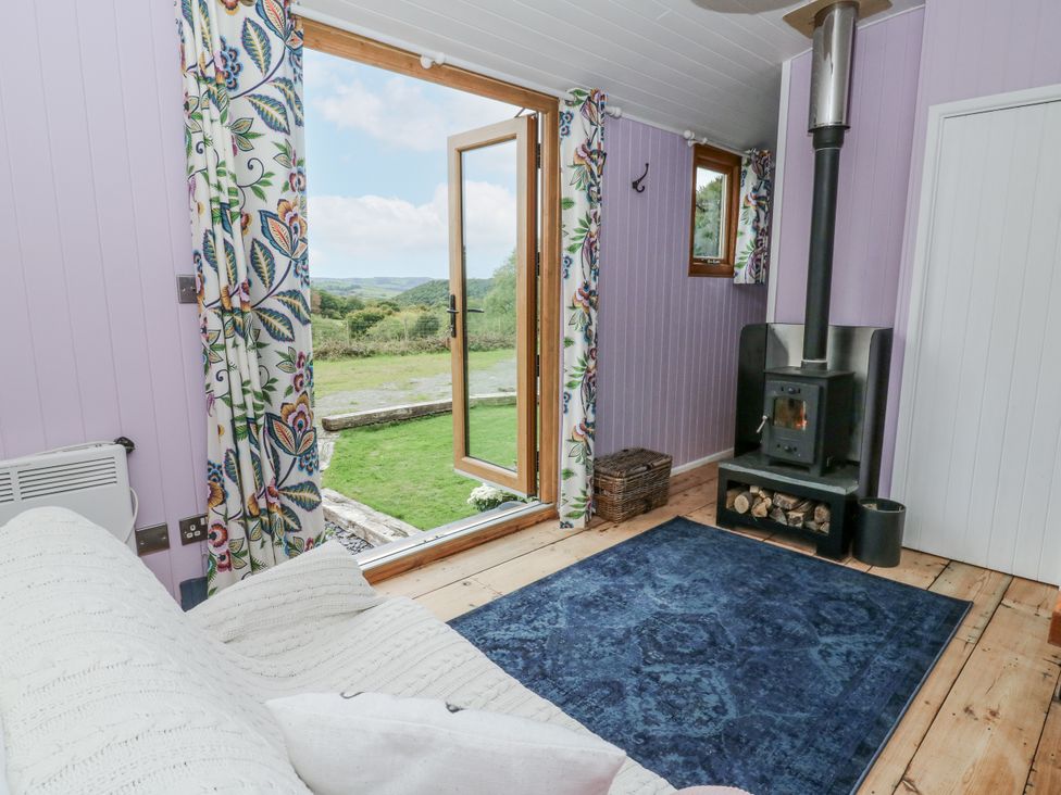 A living room with a wood stove and windows at Brondel Luxury Shepherd's Hut