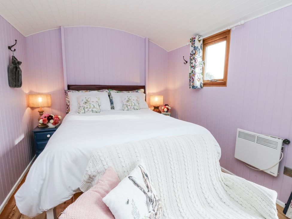 A bedroom with a bed and nightstand at Brondel Luxury Shepherd's Hut 
