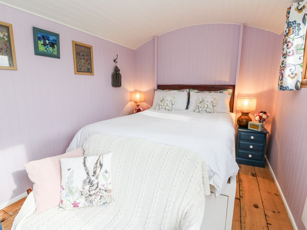 A bedroom with a bed and paintings at Brondel Luxury Shepherd's Hut