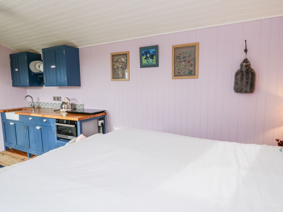 A bedroom with kitchen area and wall art at Brondel Luxury Shepherd's Hut