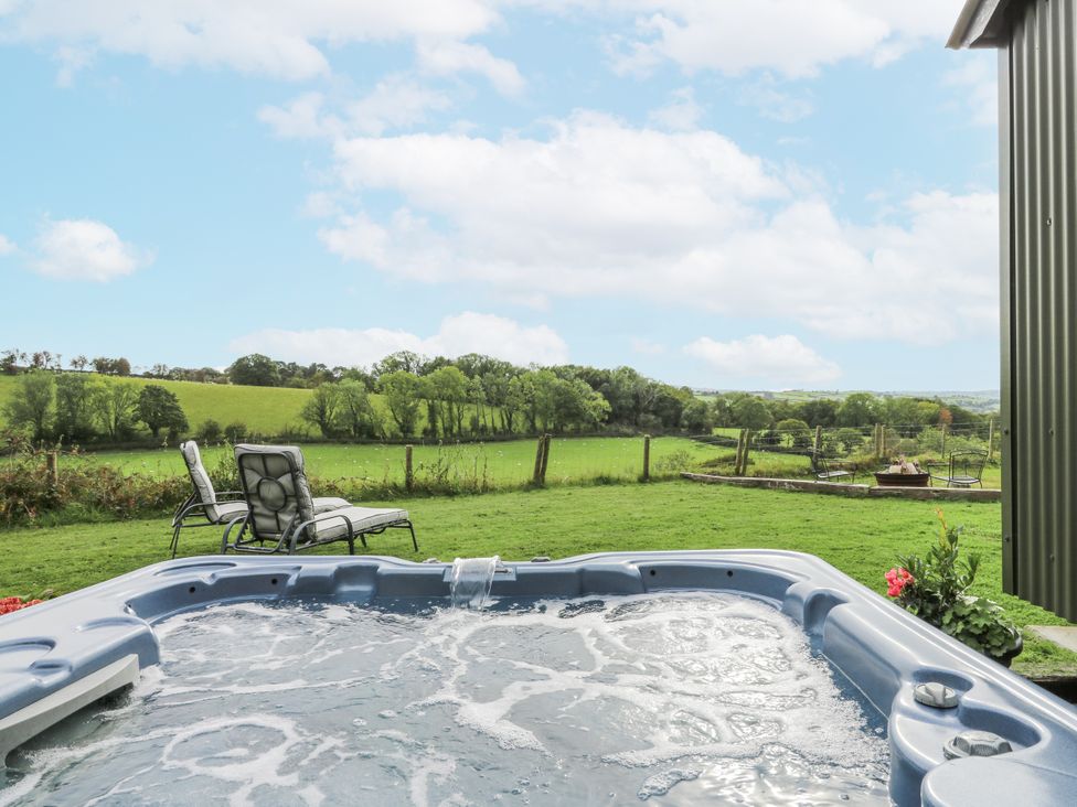 A hot tub with outdoor chairs and a green landscape at Brondel Luxury Shepherd's Hut in 