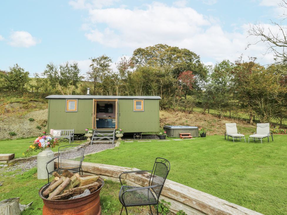 A garden with a shepherd's hut and a hot tub at Brondel Luxury Shepherd's Hut