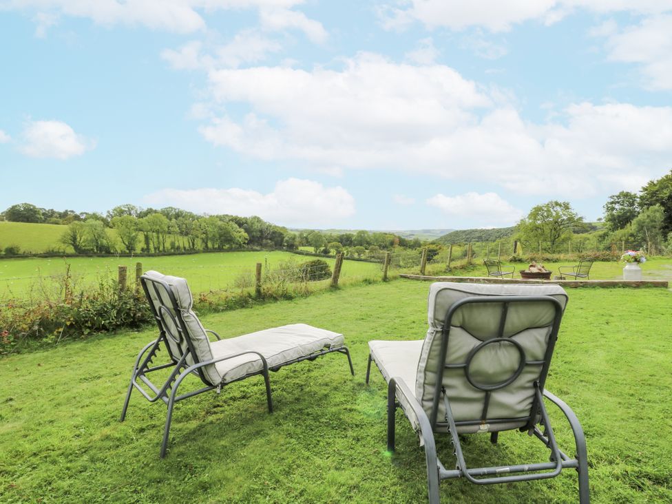 A garden with lounge chairs overlooking a green field at Brondel Luxury Shepherd's Hut