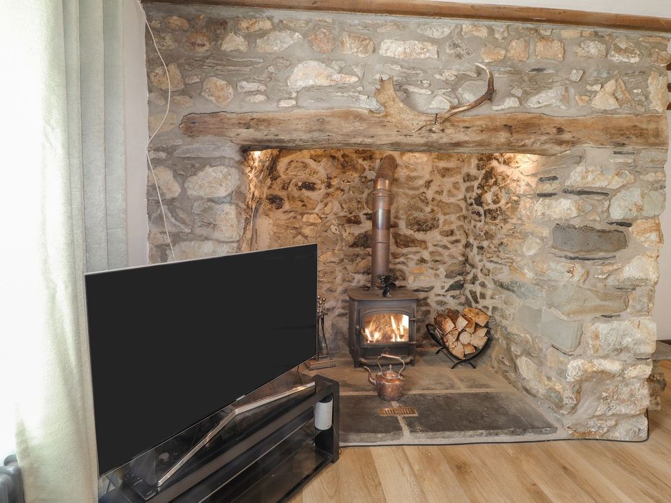 A living room with a wood stove and television at Clawddcam in Mathry
