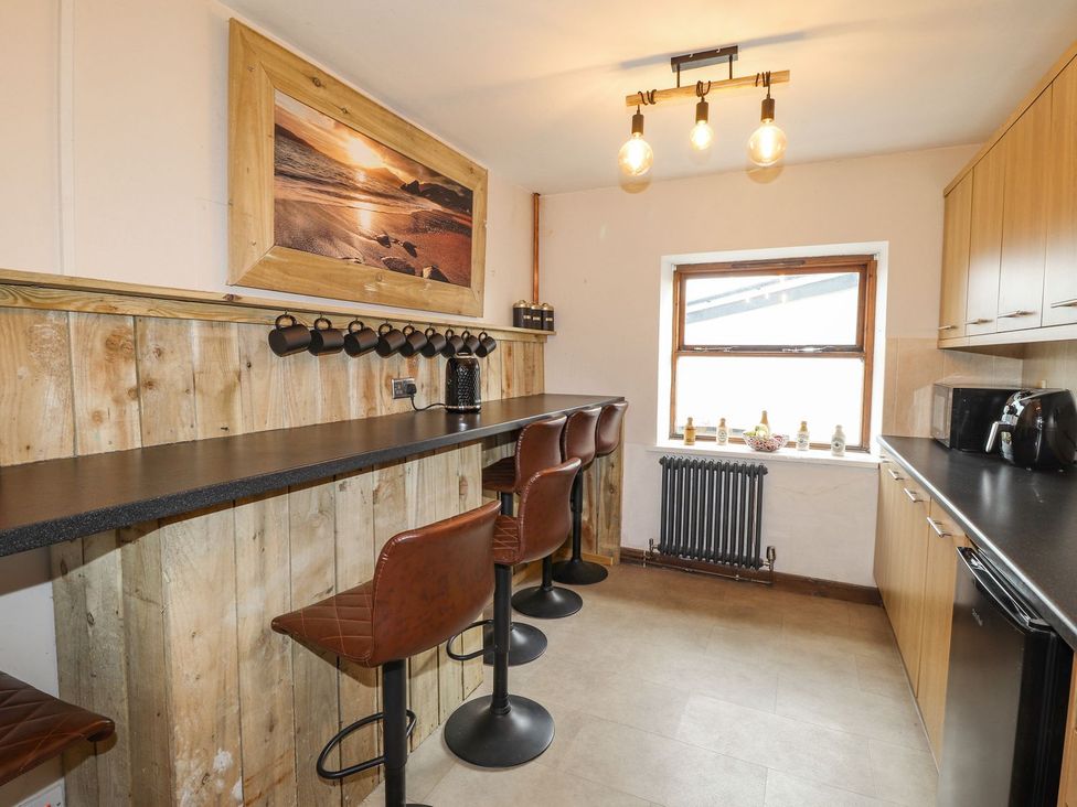 A kitchen with bar stools and a counter at Clawddcam in Mathry