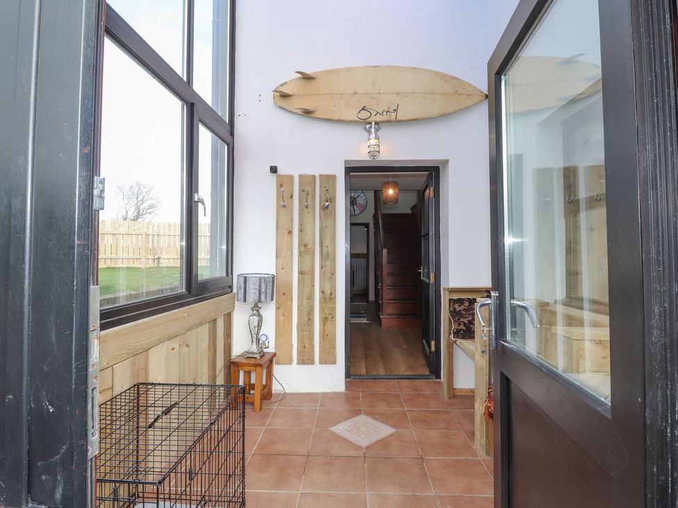 An entrance hall with a surfboard on the wall at Clawddcam in Mathry