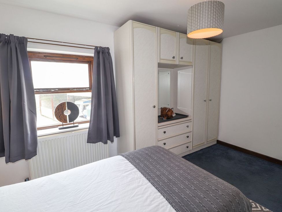 A bedroom with a bed and a wardrobe at Clawddcam Mathry