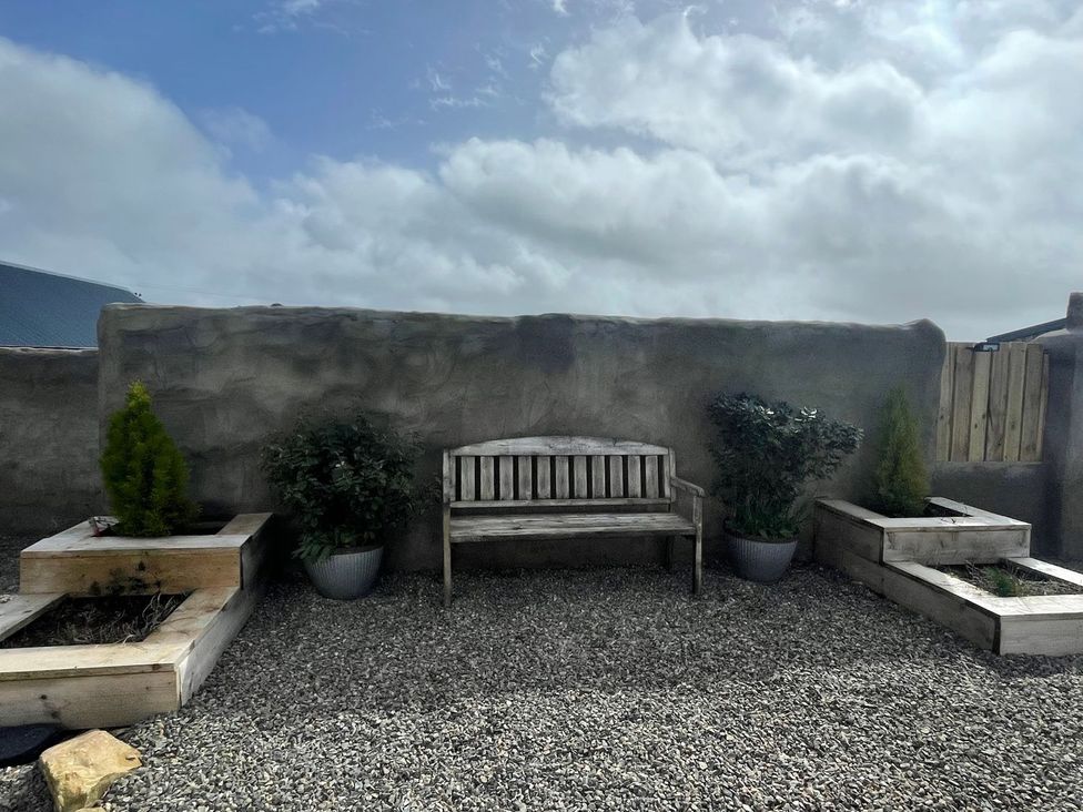 A garden with a bench and planters at Clawddcam in Mathry